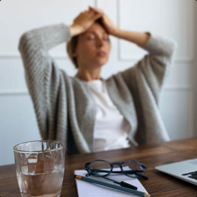 Vrouw zit met hoofdpijn aan tafel