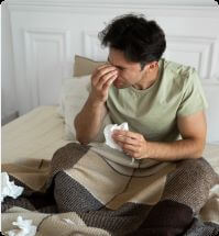 man verkouden op bed met tissues