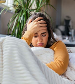 vrouw met hoofdpijn op de bank onder een dekentje