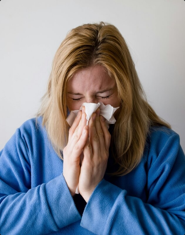 Vrouw is verkouden en snuit haar neus in een tissue