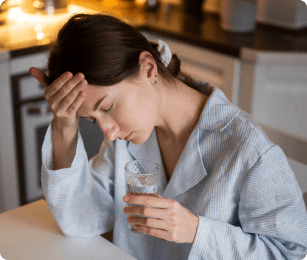 vrouw heeft hoofdpijn zit aan tafel met glas water