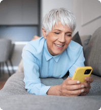 vrouw ligt op de bank en kijkt blij naar haar telefoon
